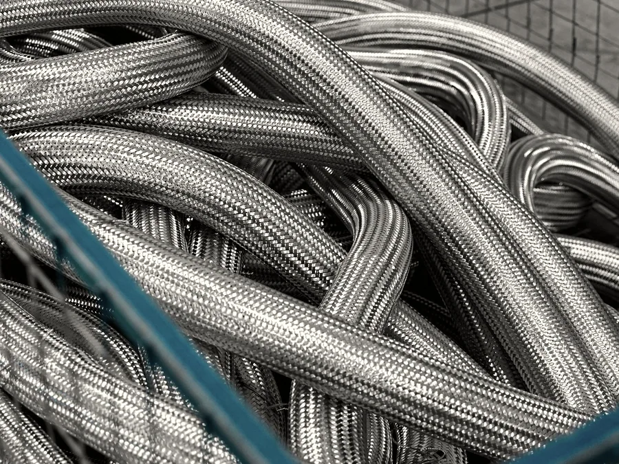 Coiled braided flexible hose stacked in a workshop bin