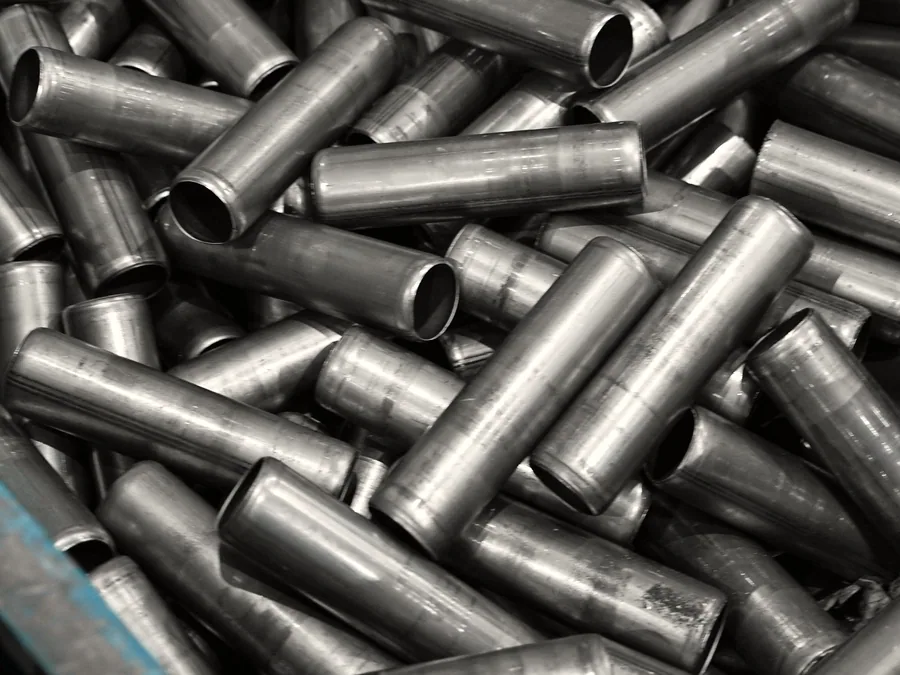 Steel sleeves with machined ends stacked in a parts bin