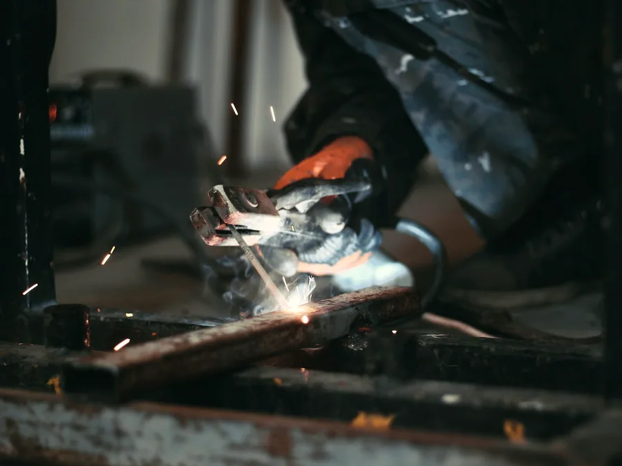 Gloved hands welding a steel joint