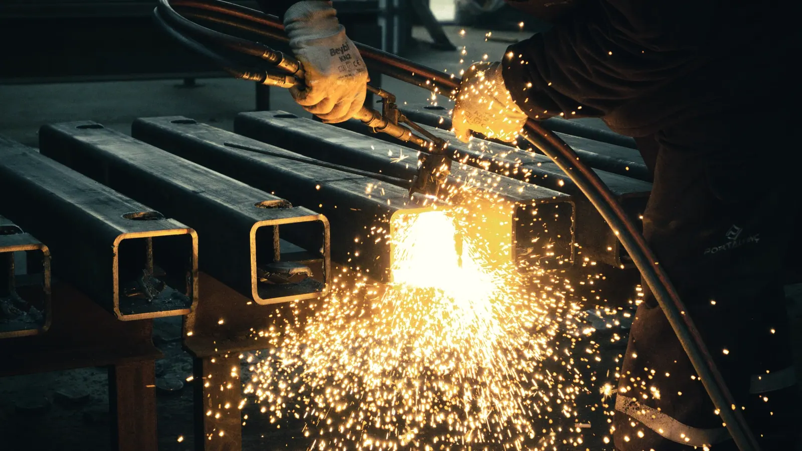 Steel section being cut, throwing sparks in a fabrication shop