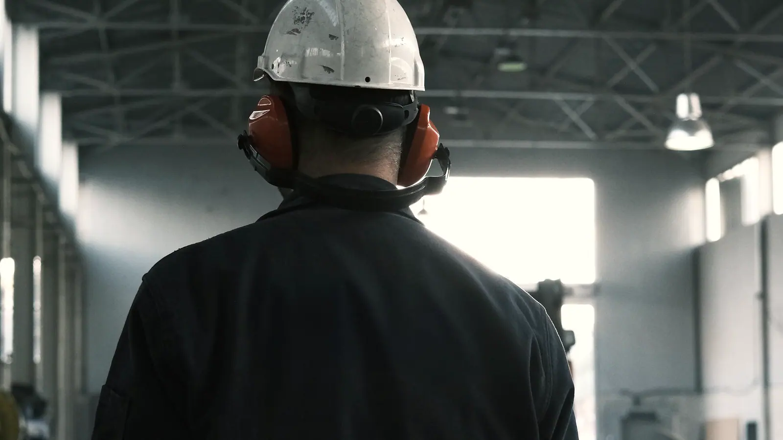 Worker in protective clothing and ear defenders on a plant floor