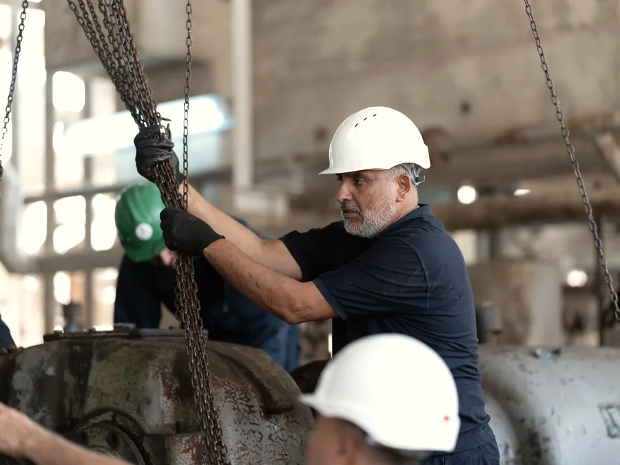 Engineer in a hard hat rigging equipment on an industrial site