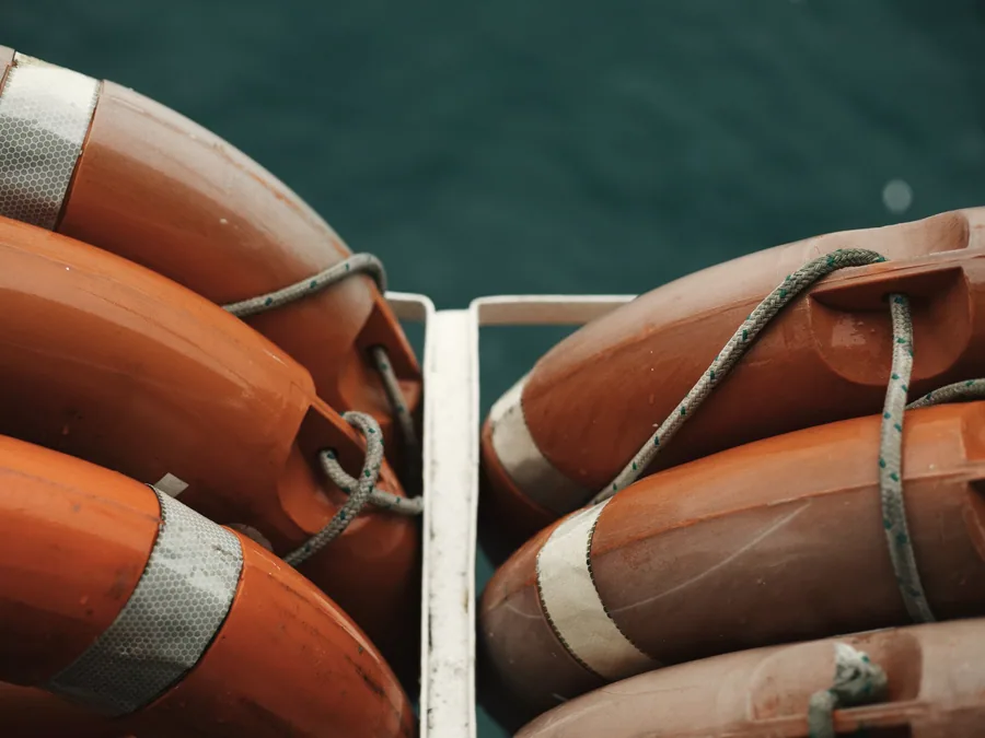 Orange lifebuoys stacked on a harbour quayside