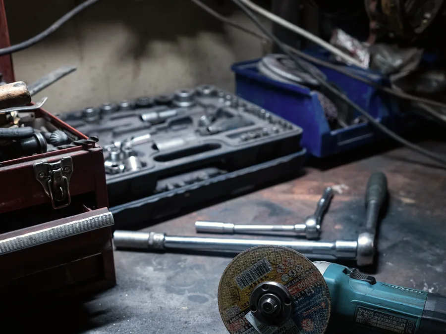 Angle grinder, socket set and eye protection on a workshop bench