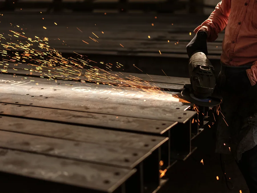 Steel plate being cut with an angle grinder in a fabrication workshop